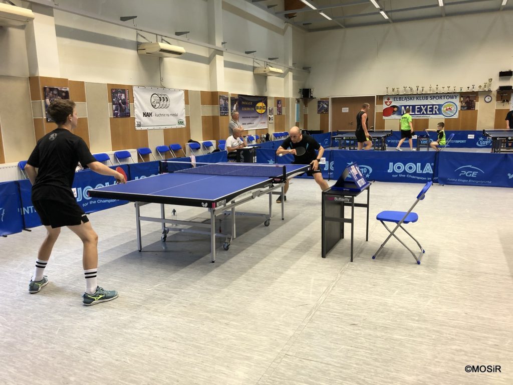 Grup mężczyzn gra w tenisa stołowego w hali