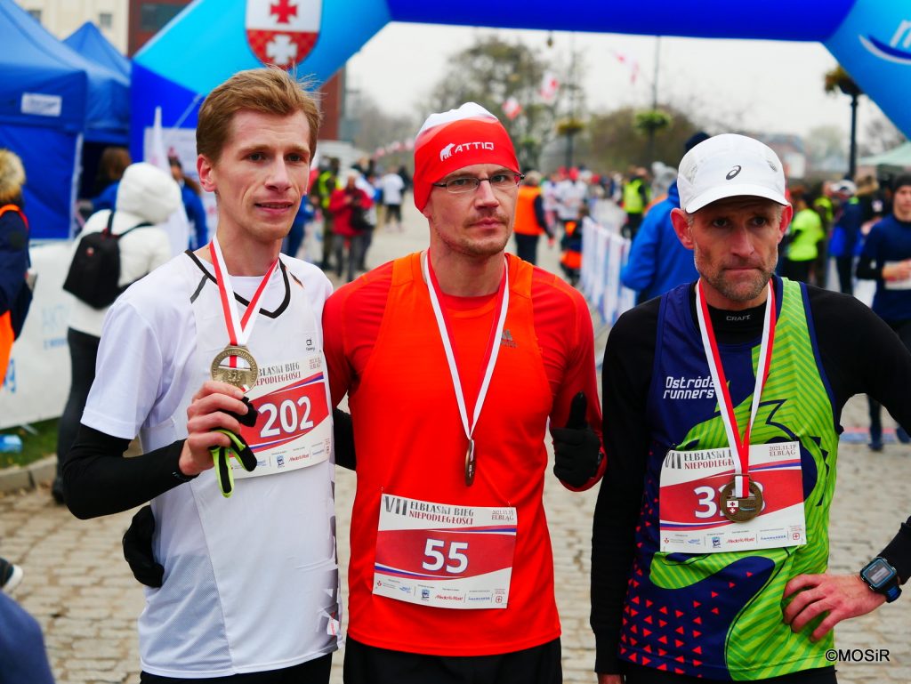 Trzech biegaczy stoi z medalami
